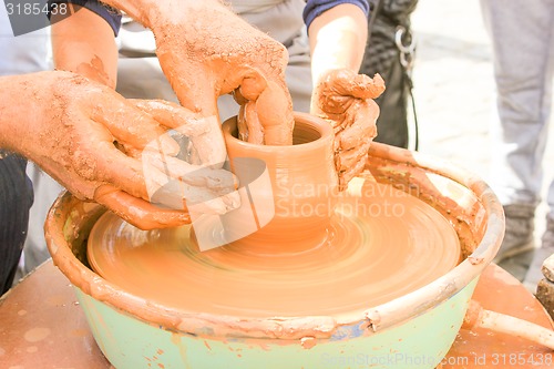 Image of Hands working on pottery wheel. 