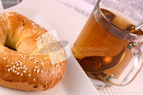 Image of cup of tea and some cookies on white material background