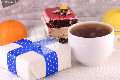 Image of glass cup of tea, gift box and chocolate cake