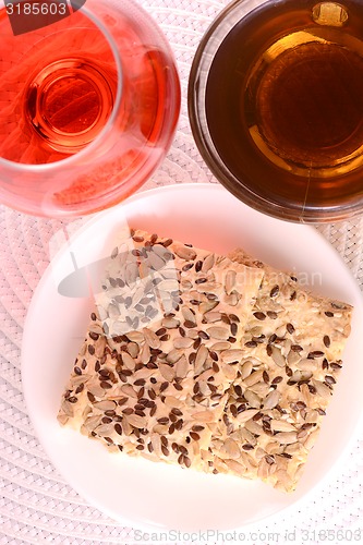 Image of sweet cake on white plate, red wine and tea cup