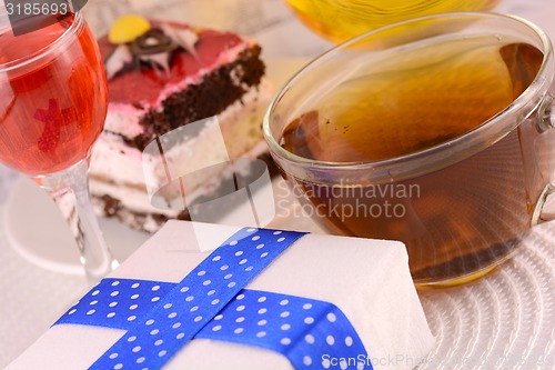 Image of glass cup of tea, gift box and chocolate cake