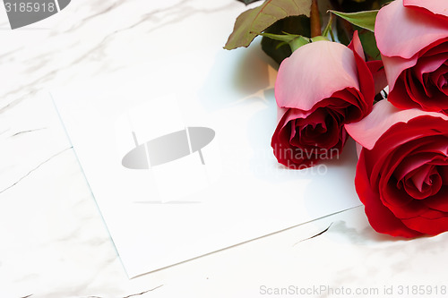 Image of roses and a blank sheet of paper on a marble surface