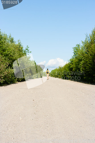 Image of man with a backpack goes on the sandy road. traveler