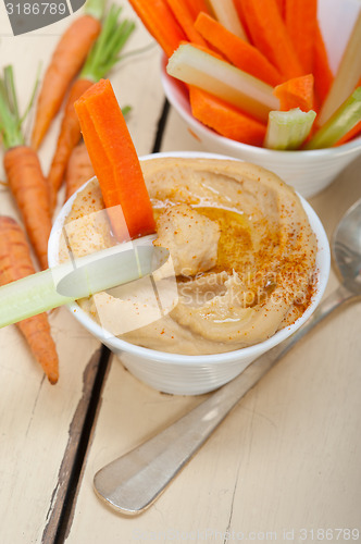 Image of fresh hummus dip with raw carrot and celery 