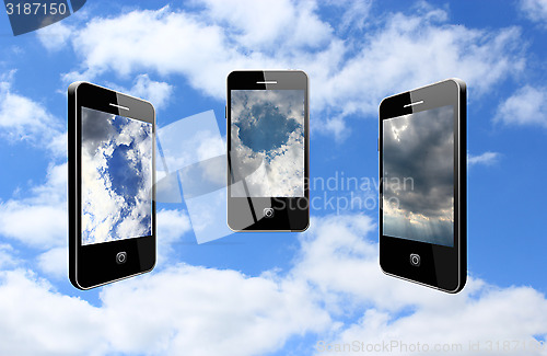 Image of three modern mobile phones on the cloudy sky