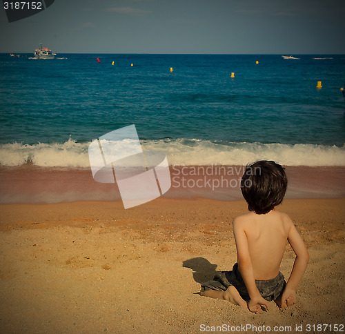 Image of boy on the beach watching at the sea