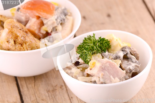 Image of Fresh salad on white bowl and chicken legs