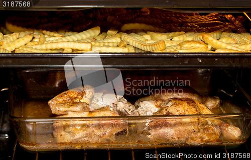 Image of fresh chicken and french fries in oven