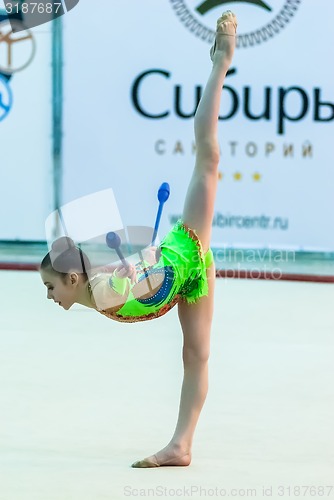 Image of Young beautiful girl shows exercise with maces