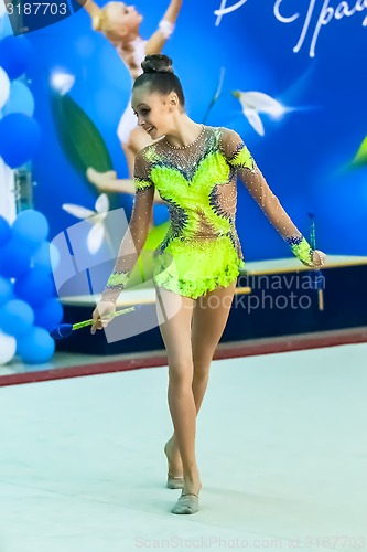 Image of Young beautiful girl shows exercise with maces