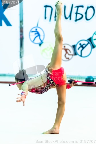 Image of Young beautiful girl shows exercise with maces