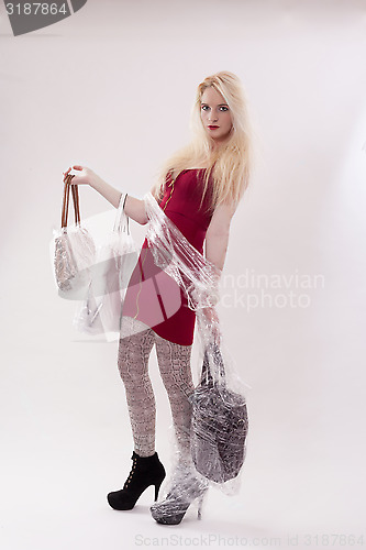 Image of Young woman with long blond hair and three handbags in hand