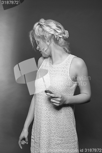 Image of Blonde girl in mini dress and stylish hairstyle with biscuit in hand looks back over her shoulder