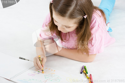 Image of girl draws lying on the floor