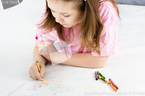 Image of girl draws lying on the floor