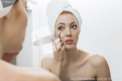 Image of Woman After Shower Applying Cream on her Face