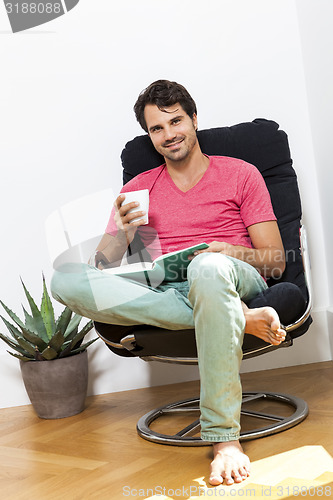 Image of Man Sitting on Chair with Book and a Drink