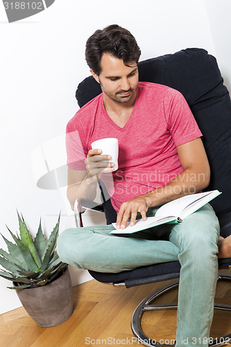 Image of Man Sitting on Chair with Book and a Drink