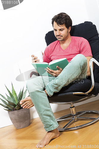 Image of Man Sitting on Chair with Book and a Drink