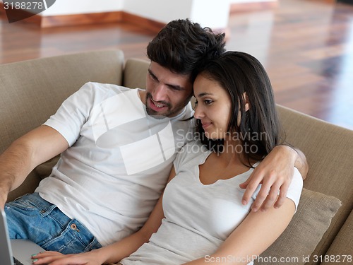 Image of relaxed young couple working on laptop computer at home