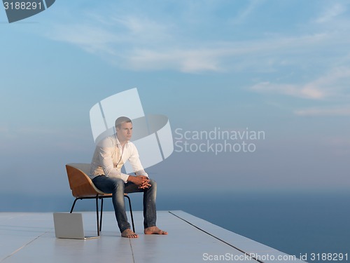 Image of relaxed young man at home on balcony