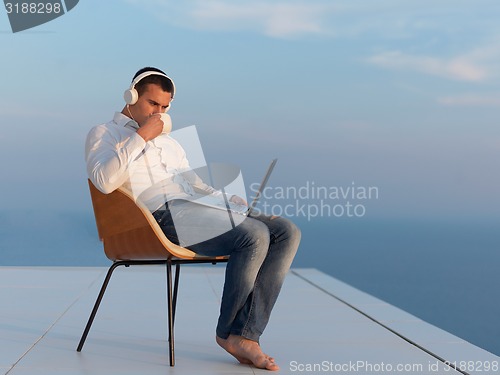 Image of relaxed young man at home on balcony