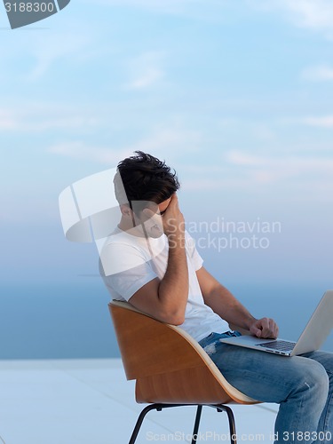 Image of relaxed young man at home on balcony