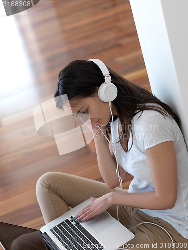 Image of relaxed young woman at home working on laptop computer