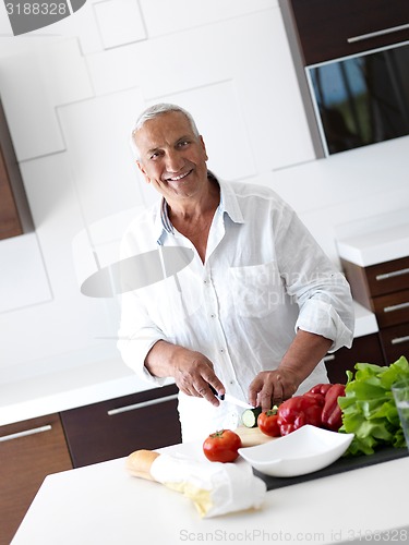 Image of man cooking at home preparing salad in kitchen