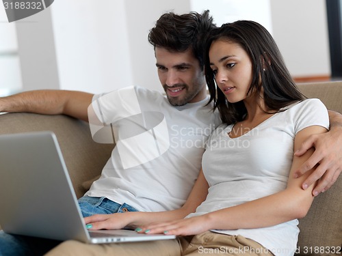 Image of relaxed young couple working on laptop computer at home