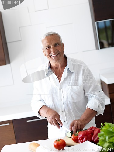 Image of man cooking at home preparing salad in kitchen