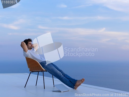 Image of relaxed young man at home on balcony