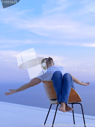 Image of relaxed young man at home on balcony