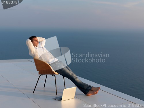 Image of relaxed young man at home on balcony