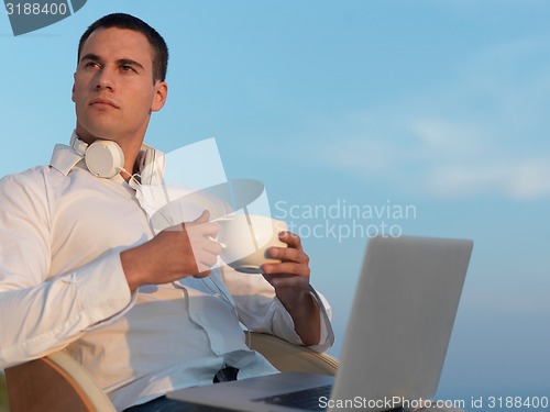 Image of relaxed young man at home on balcony