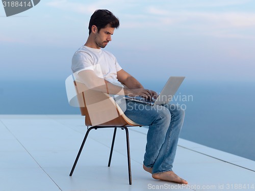 Image of relaxed young man at home on balcony