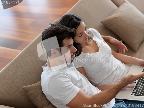 Image of relaxed young couple working on laptop computer at home