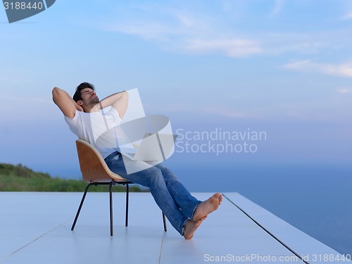 Image of relaxed young man at home on balcony