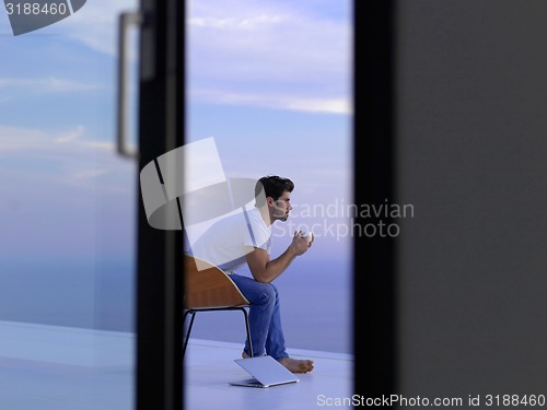 Image of relaxed young man at home on balcony