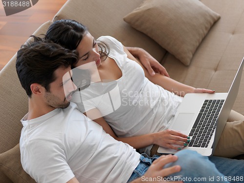 Image of relaxed young couple working on laptop computer at home