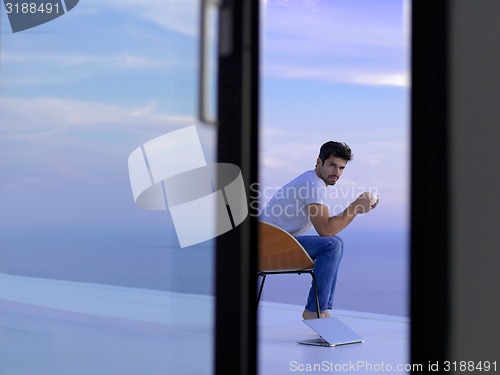Image of relaxed young man at home on balcony