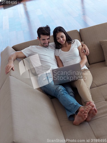 Image of relaxed young couple working on laptop computer at home