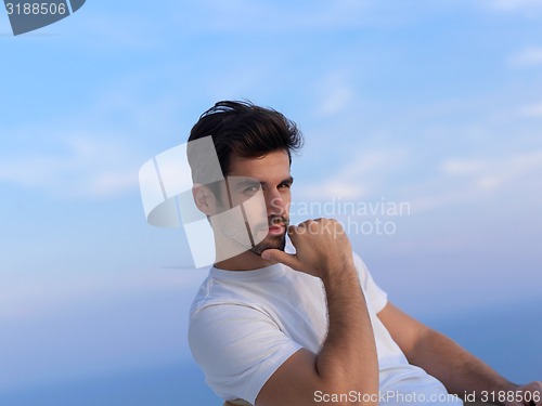 Image of relaxed young man at home on balcony