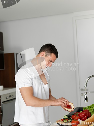 Image of man cooking at home preparing salad in kitchen