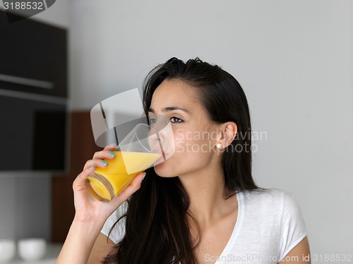 Image of woman drinking juice in her kitchen