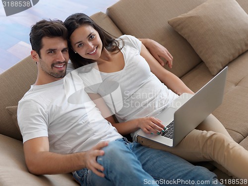 Image of relaxed young couple working on laptop computer at home