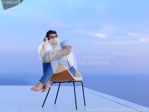 Image of relaxed young man at home on balcony