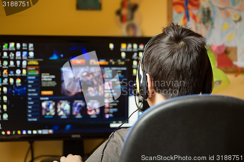 Image of Boy using computer at home, playing game