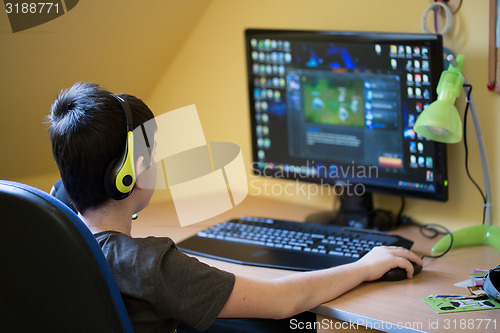 Image of Boy using computer at home, playing game