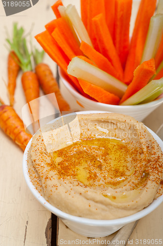 Image of fresh hummus dip with raw carrot and celery 